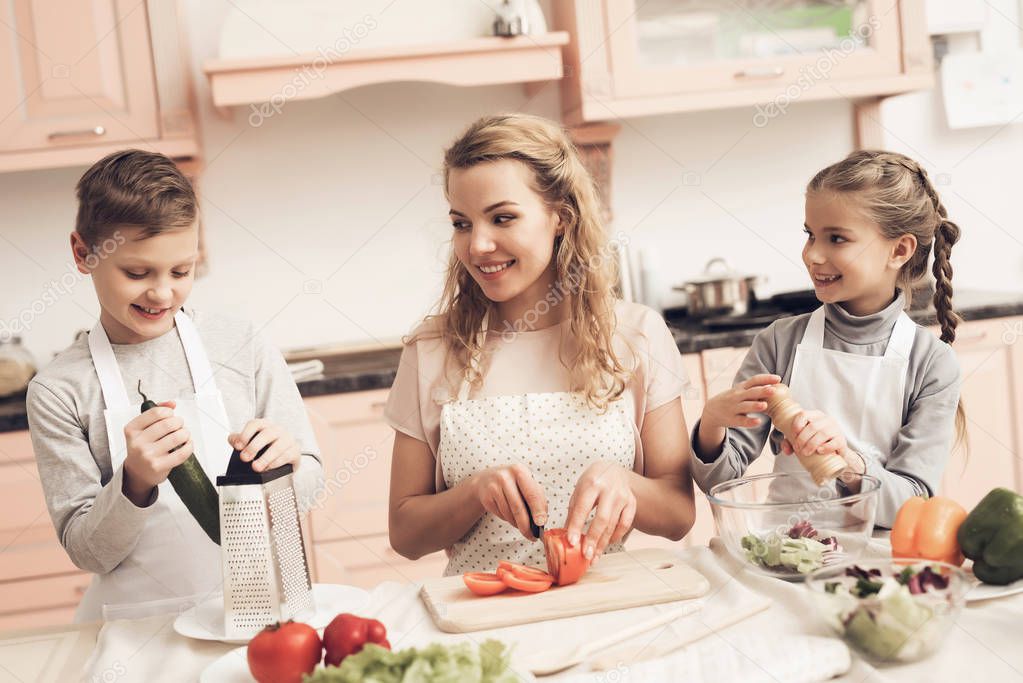 Children with mother preparing vegetables for salad at kitchen 