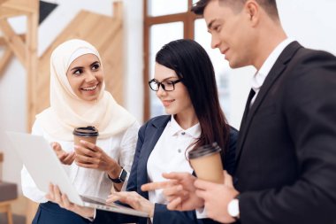İki kadın ve erkek kahve içme ve dizüstü bilgisayar ekranında bir şey izliyor