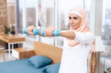 Arap kadın dumbbells ile yatak odasında jimnastik yapıyor  