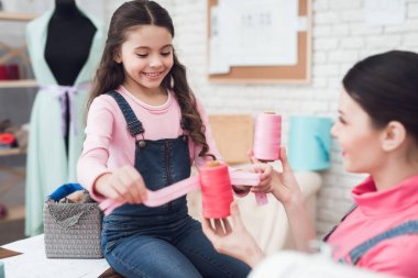 Dikiş Atölyesi ve kurdeleler tutan anne ve kızı birlikte çalışır