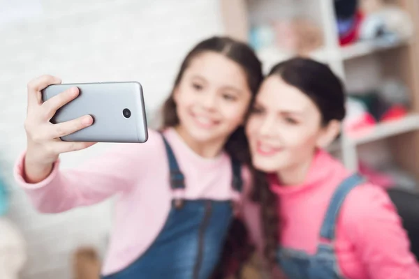 Mom with daughter making selfie on smartphone while they working together in sewing workshop