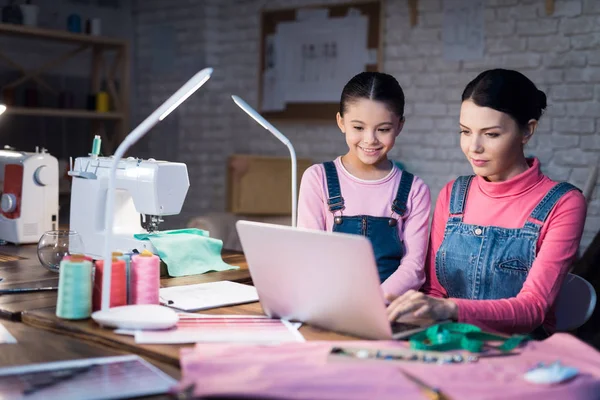 Erwachsene Frau Tippt Computer Während Tochter Neben Ihr Nähwerkstatt Steht — Stockfoto