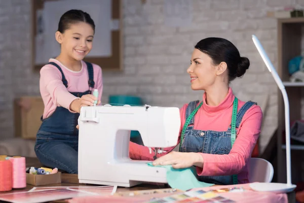 Mom and daughter working together and creating clothes in sewing workshop