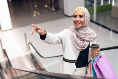 Arap kadın alışveriş merkezi alışveriş torbaları ve kahve ile yürüyüş