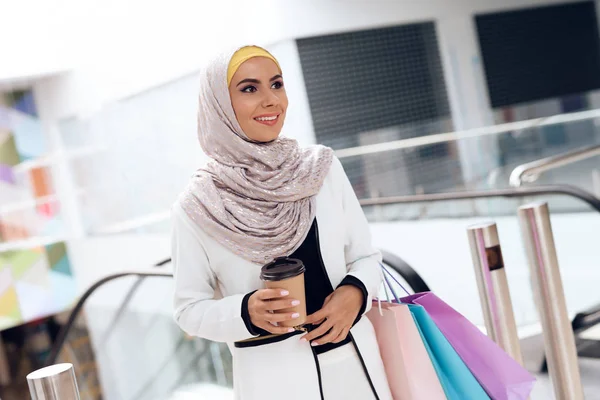 Arab woman walking in shopping mall with shopping bags and coffee