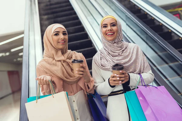 Arab women walking in shopping mall with coffee