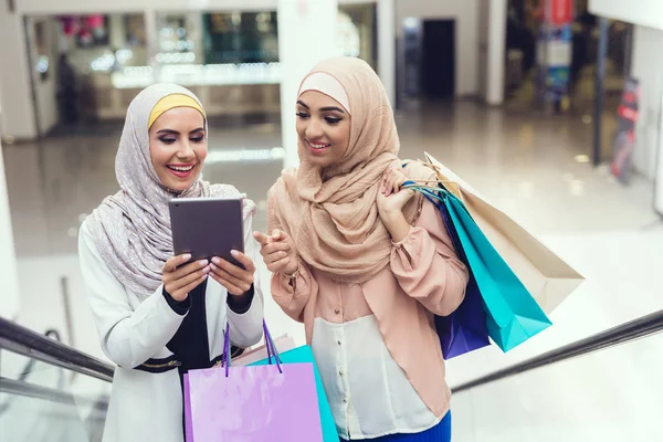 Arab women using tablet pc after shopping at mall