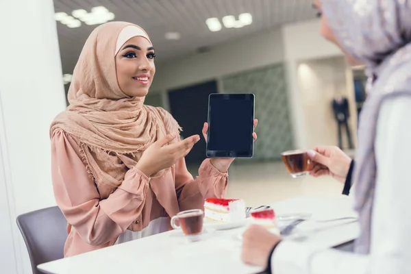 Arab women using tablet pc after shopping at mall