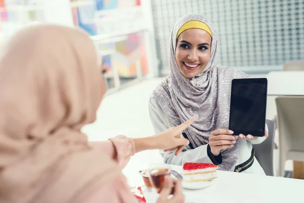 Arab women using tablet pc after shopping at mall