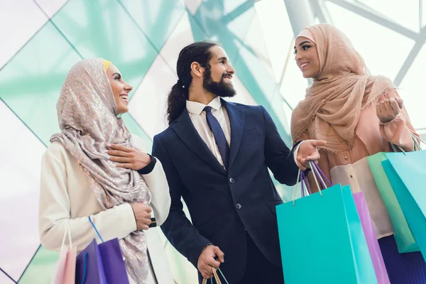 Arab women and man holding shopping bags at mall