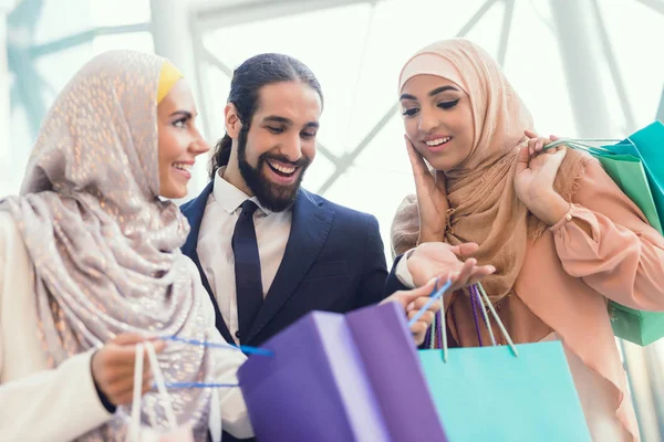 Arab women and man holding shopping bags at mall