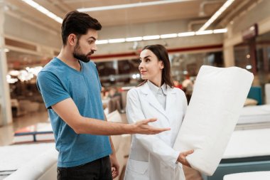 adama mobilya mağazasında Ortopedik yastık gösteren danışman