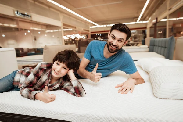有胡子的父亲与小儿子测试床垫为柔软在商店 — 图库照片