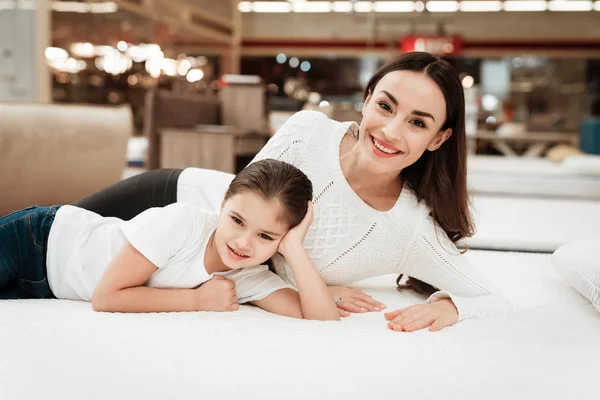 mother with daughter lying on bed in mattress store