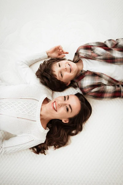 mother and son lying on bed in mattress store