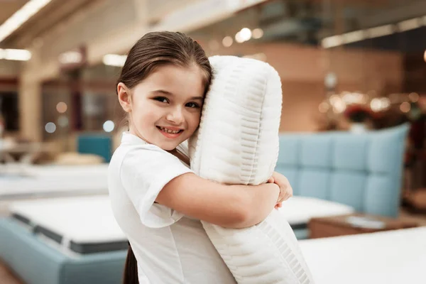 little girl testing softness of mattress in furniture store