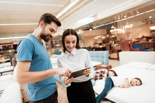 female consultant with man making out purchase of mattress in store