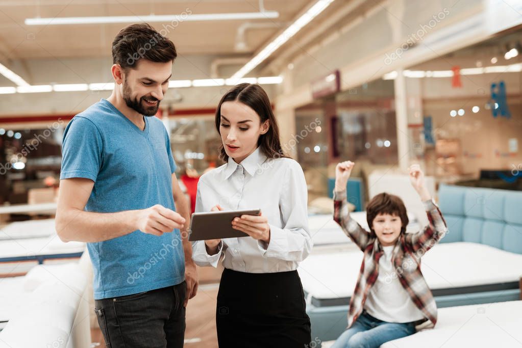 female consultant with man making out purchase of mattress in store