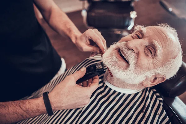 Barber trimming beard to client in salon