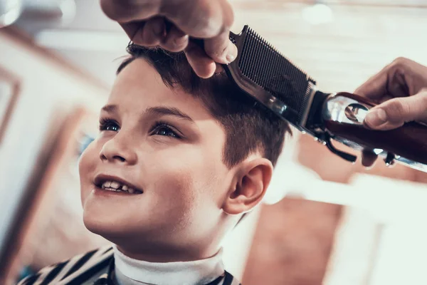 Hairdresser making haircut by hair trimmer in barbershop