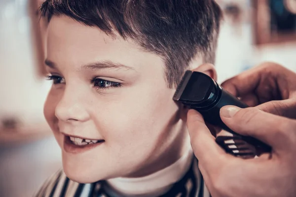 Hairdresser making haircut by hair trimmer in barbershop