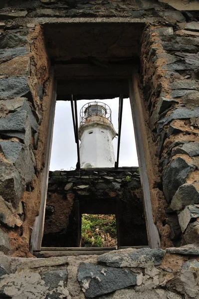 Viejo faro a través del agujero de la ventana de la casa en ruinas — Foto de Stock