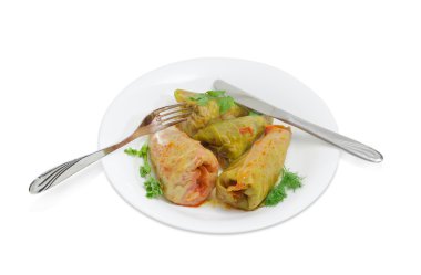 Cooked cabbage rolls, fork and knife on white dish clipart