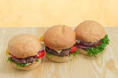 Üç hamburger bir ahşap yüzeye