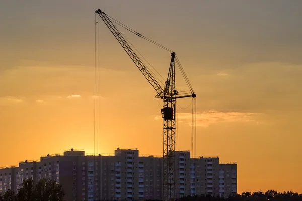 Tower crane on background of building and sky during sunset — Stock Photo, Image