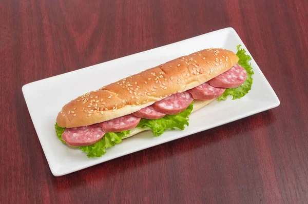 Сэндвичи с булочкой, колбасой и салатом на прямоугольном диске — стоковое фото