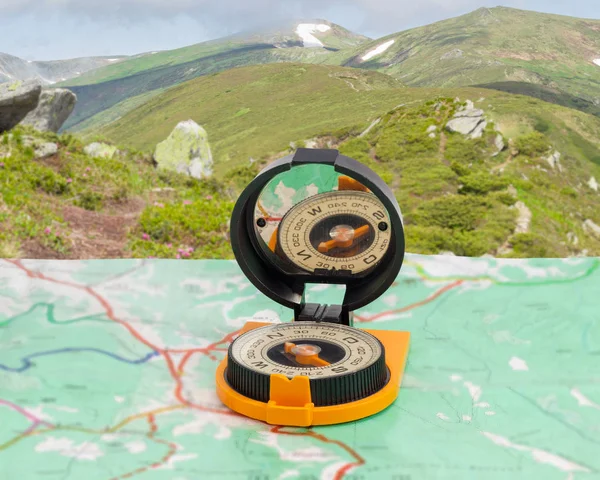 Magnetisk kompass på turistkarta på bakgrund av bergskedjan — Stockfoto