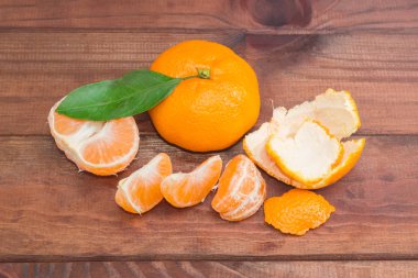 Koyu ahşap yüzeyde bir bütün ve soyulmuş mandalina