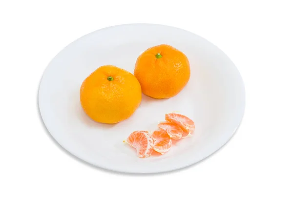 Dois inteiros e segmentos de laranjas de tangerina em prato branco — Fotografia de Stock