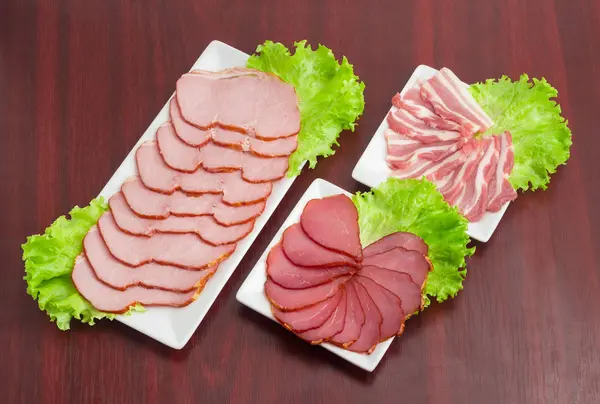 Řezy různými připravené vepřové maso s hlávkovým salátem na obdélníkové misky — Stock fotografie