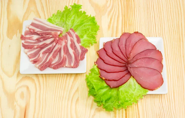 Нарезанный бекон и излеченная свиная вырезка на квадратной тарелке — стоковое фото