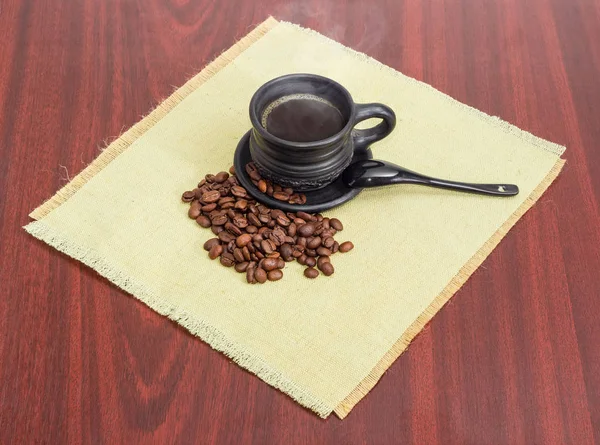 コーヒー豆と黒セラミック カップに淹れたてのコーヒー — ストック写真