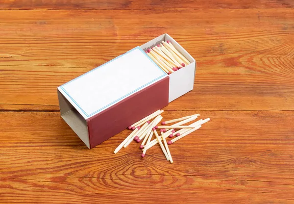 Wooden safety matches in large matchbox and several matches beside