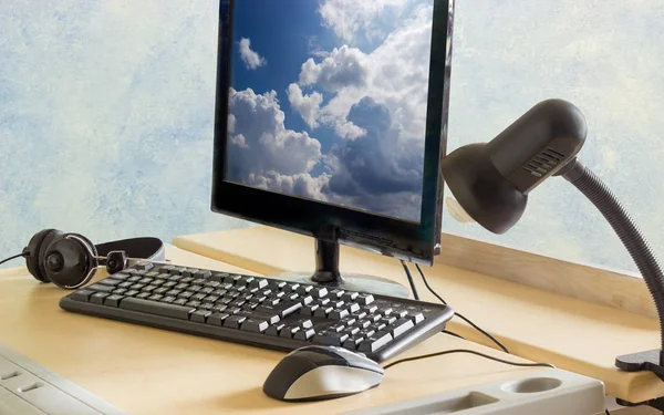 Monitor, keyboard, mouse, headphones and light fixture on a desk Stock Picture