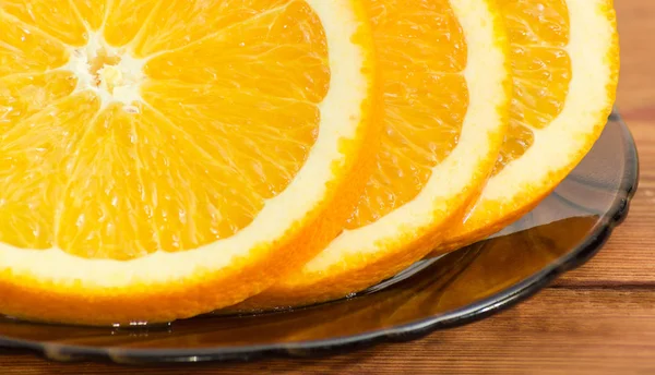 Фрагмент оранжевых ломтиков на стеклянной тарелке крупным планом — стоковое фото