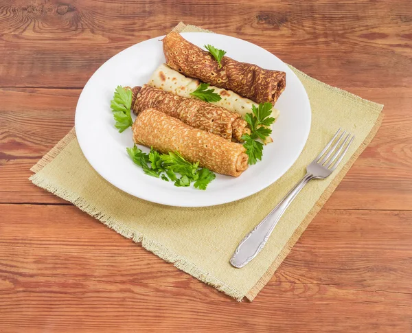 Блинчики с начинкой из мяса на белом блюде и вилке — стоковое фото