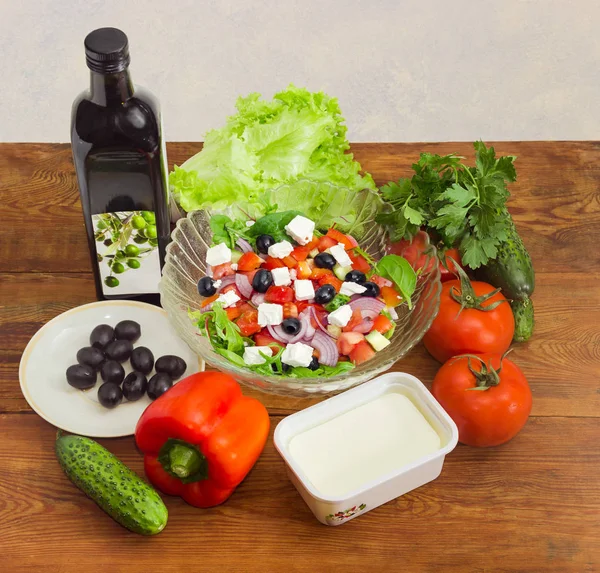 Salade grecque parmi les ingrédients pour sa cuisson sur une surface en bois — Photo