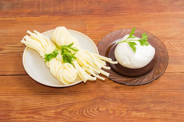 Dos variedades de queso mozzarella con perejil en superficie de madera — Foto de Stock