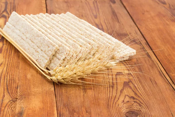Pão crocante de grãos múltiplos com espigas de trigo na superfície de madeira closeup — Fotografia de Stock
