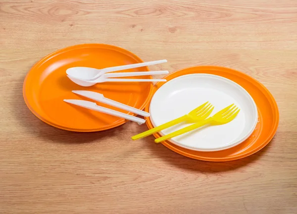Plaques, cuillères, fourchettes et couteaux jetables en plastique orange et blanc — Photo