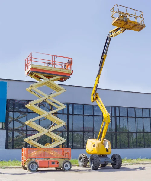 Tesoura e lança articulada elevadores de rodas no solo asfáltico — Fotografia de Stock