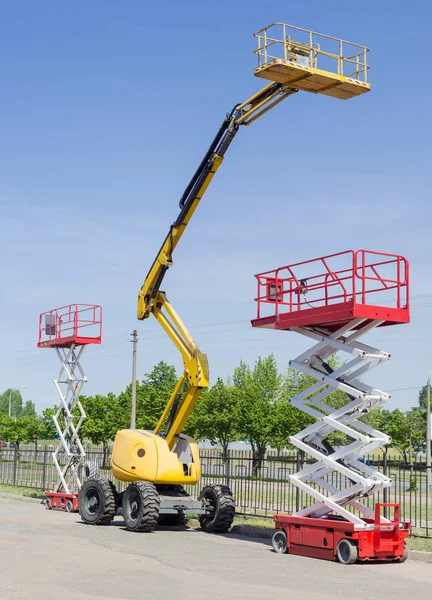 Zwei Scheren- und eine Gelenkarmhebebühne auf Asphaltboden — Stockfoto