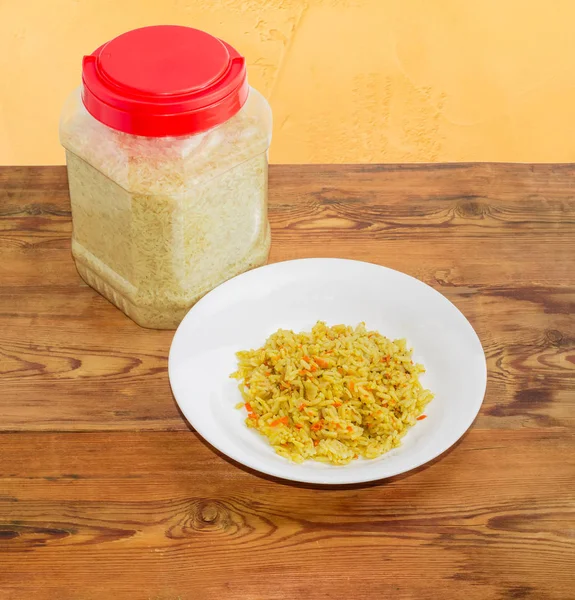 Варений рис на тарілці та неварений рис у пластиковій тарі — стокове фото