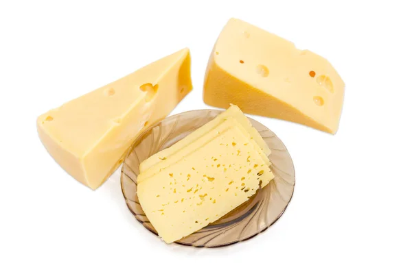 Fromage tranché sur une soucoupe et deux morceaux de fromage à côté — Photo