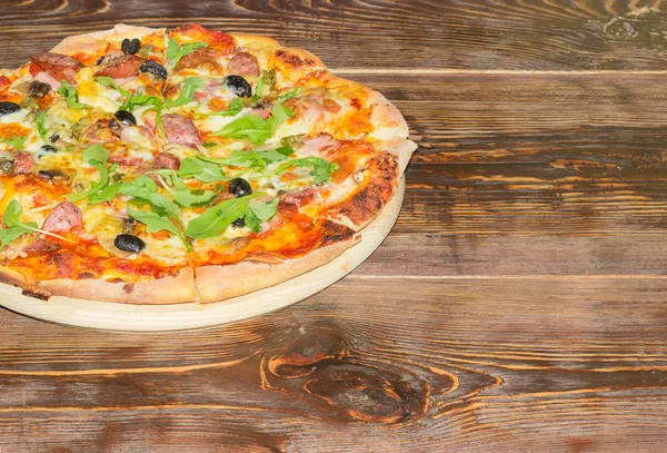 Eski ahşap bir masa üzerinde pişmiş pizza — Stok fotoğraf