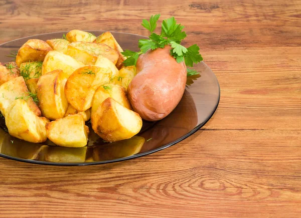 Жареный картофель с сосисками на стеклянной тарелке крупным планом — стоковое фото